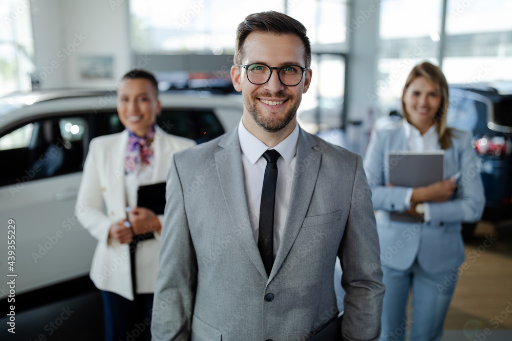 salesteam in dealership, three beautiful consultants or managers in elegant suit looking on camera. salesteam in dealership, three beautiful consultants or managers in elegant suit looking on camera.