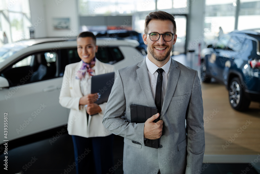 Two consultants or managers in elegant suit with laptop in arms, looking on camera with smile. Two consultants or managers in elegant suit with laptop in arms, looking on camera with smile.