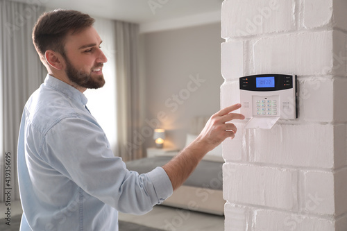 Man entering code on security alarm system at home