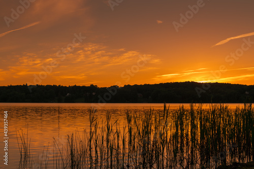 A low angle photograph of an early summer sunset from across the lake.