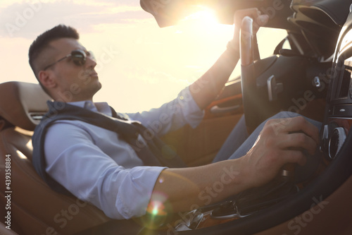 Businessman driving luxury convertible car outdoors on sunny day © New Africa