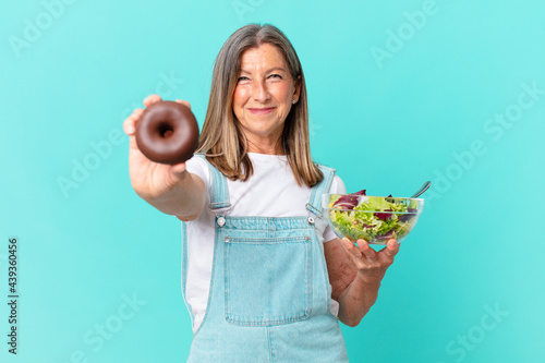 iddle age pretty woman with a donut and a salad. diet concept photo