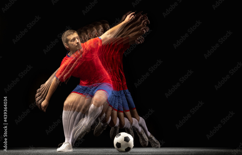 Non stop moving. Young caucasian football soccer player playing in motion in mixed light on dark background. Non stop moving. Young caucasian football soccer player playing in motion in mixed light on dark background.