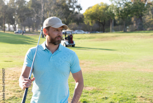 man golfer in cap with golf club on summer green grass, sport