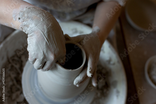 Woman making pottery on spinning wheel in her workshop