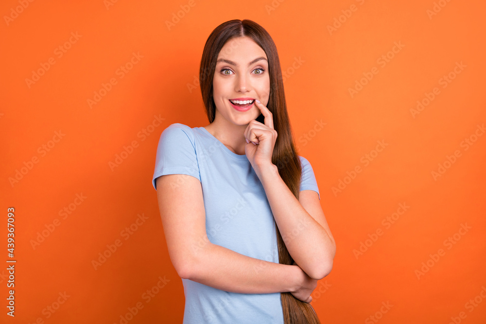 Photo of impressed straight hairdo young lady finger chin wear blue t-shirt isolated on vivid orange color background Photo of impressed straight hairdo young lady finger chin wear blue t-shirt isolated on vivid orange color background