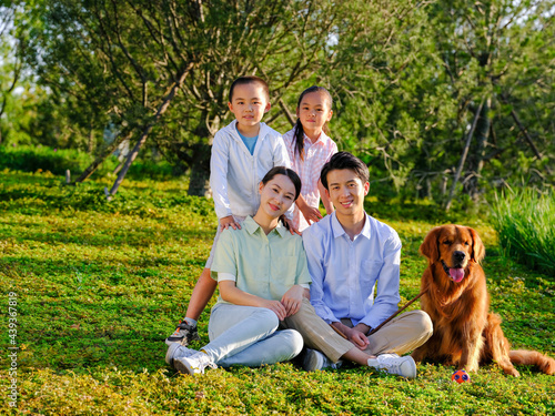 Happy family of four and pet dog in the park