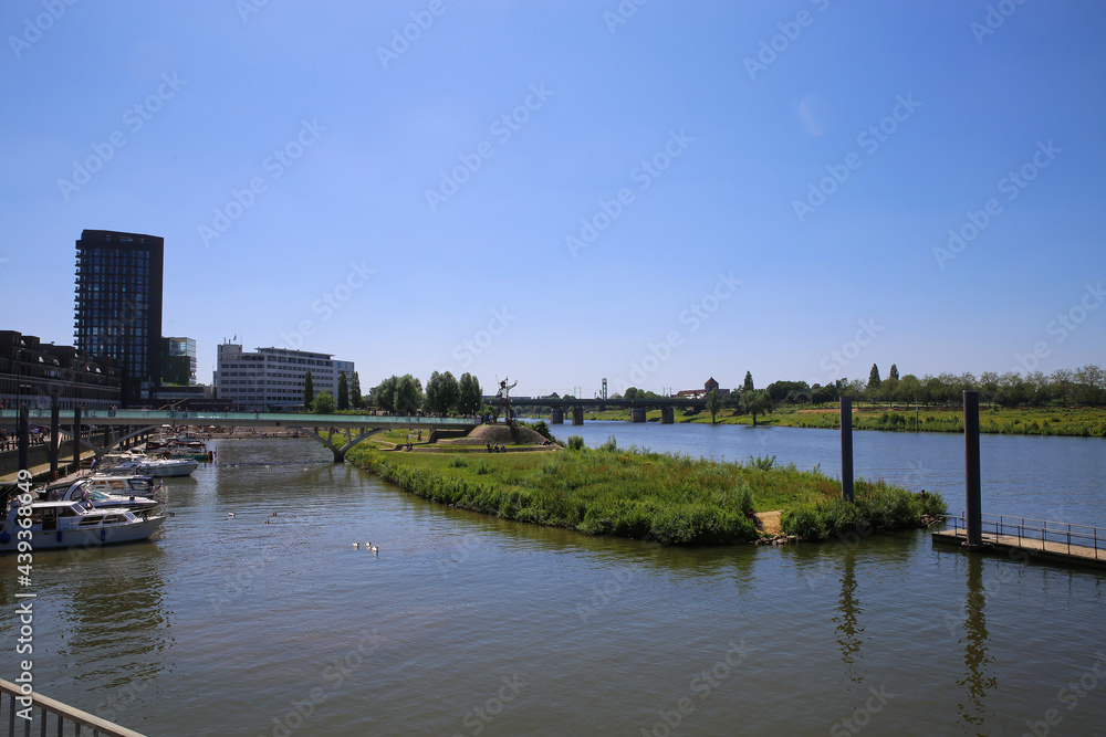 Venlo, Netherlands - June 9. 2021: View over river Maas on skyline of dutch city with harbor and boats in summer