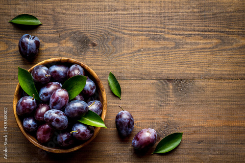 Purple plums with leaves top view. Food fruits background photo