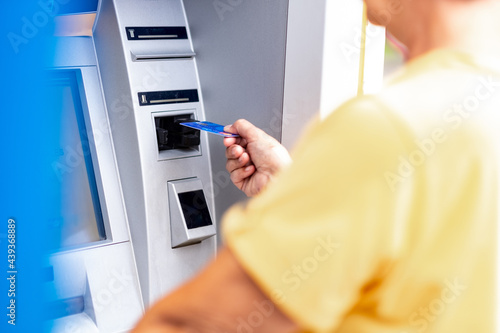 Woman yellow dressed withdrawing money from credit card at ATM