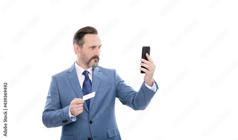 serious mature boss in suit hold credit card and phone isolated on white, selfie serious mature boss in suit hold credit card and phone isolated on white, selfie