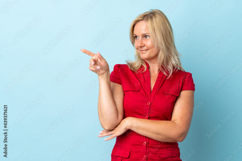 Middle age woman isolated on blue background pointing finger to the side Middle age woman isolated on blue background pointing finger to the side
