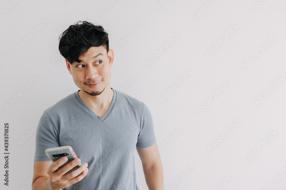 Smile Asian man is happy with the smartphone application isolated on white wall. Smile Asian man is happy with the smartphone application isolated on white wall.