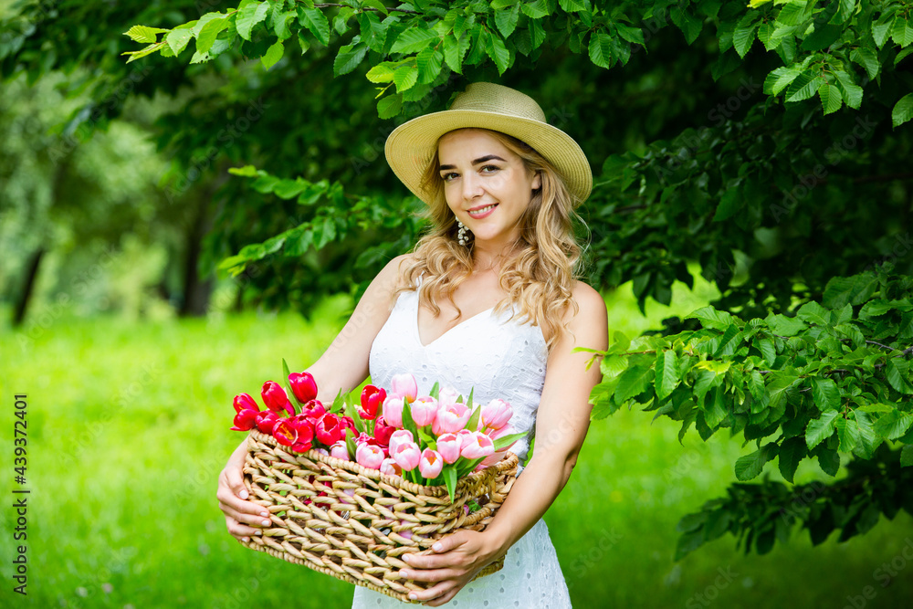 Fototapeta premium Beautiful woman resting in park sitting on a picnic blanket with fruits and wine.