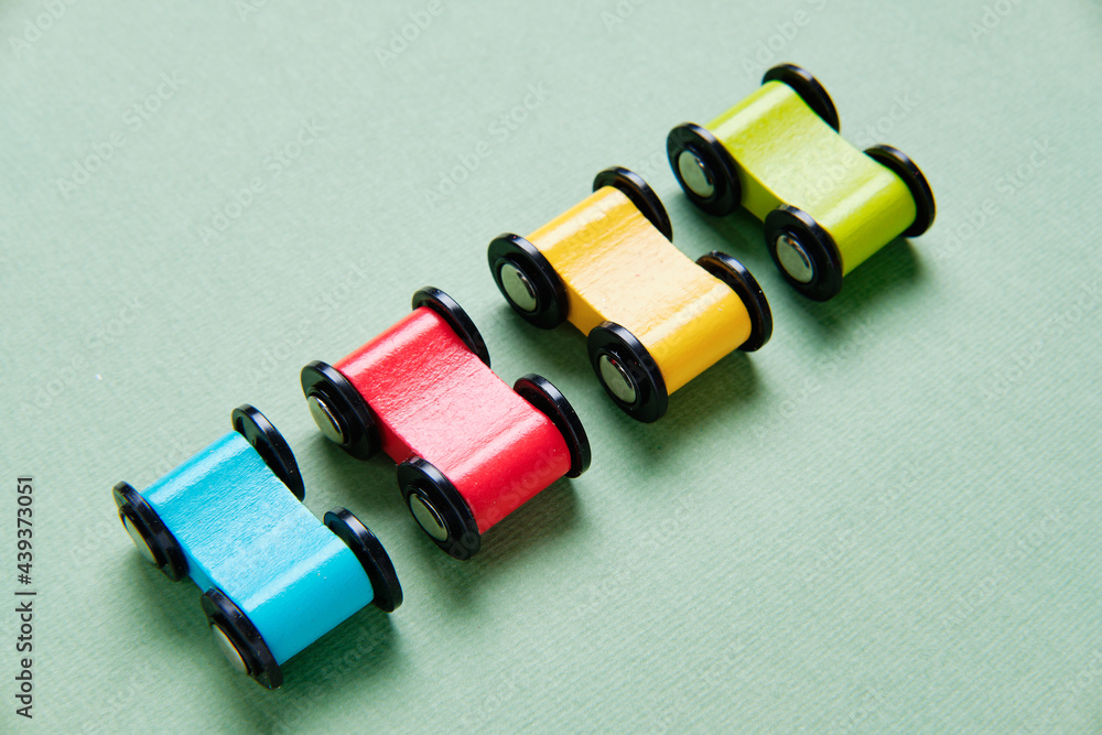 Fototapeta premium Toy cars made of wood of different colors are stand in a row. View from above.