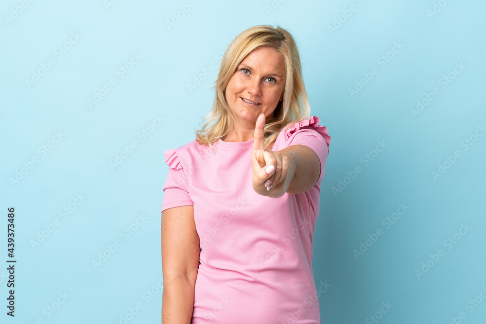 Middle age woman isolated on blue background showing and lifting a finger Middle age woman isolated on blue background showing and lifting a finger