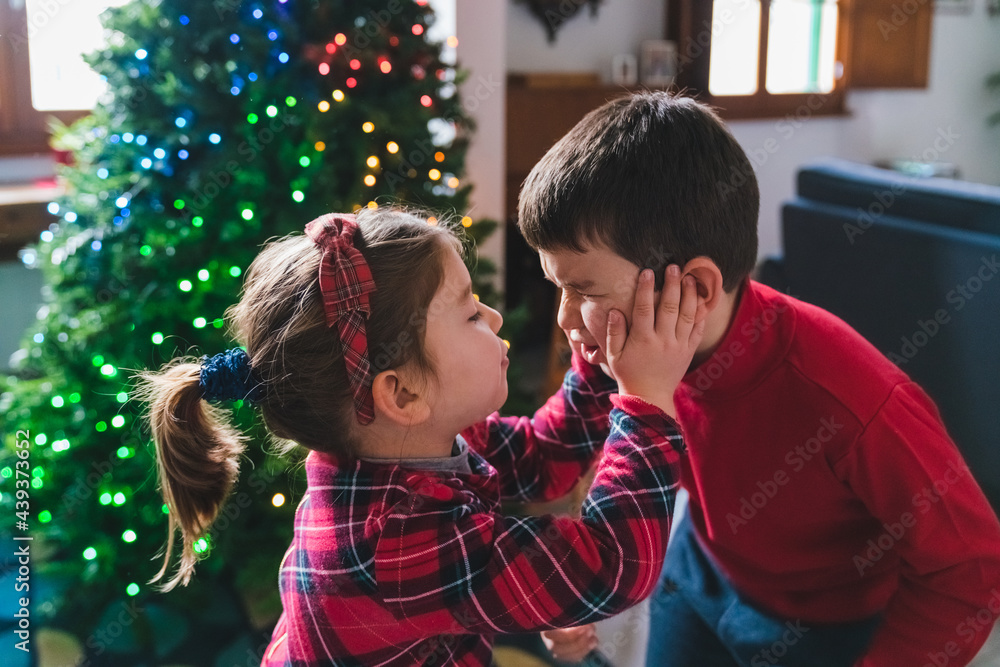 Playful Siblings at Home with Christmas Tree Playful Siblings at Home with Christmas Tree