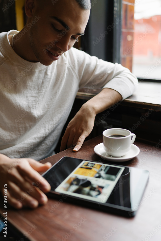 Young Man Using Computer Seated in a Coffee Shop Young Man Using Computer Seated in a Coffee Shop