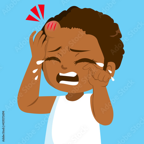 Sad little black girl crying in pain with bump bruise on forehead