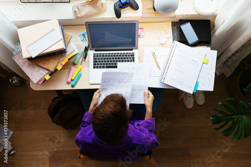 Smart kid studying papers while doing homework