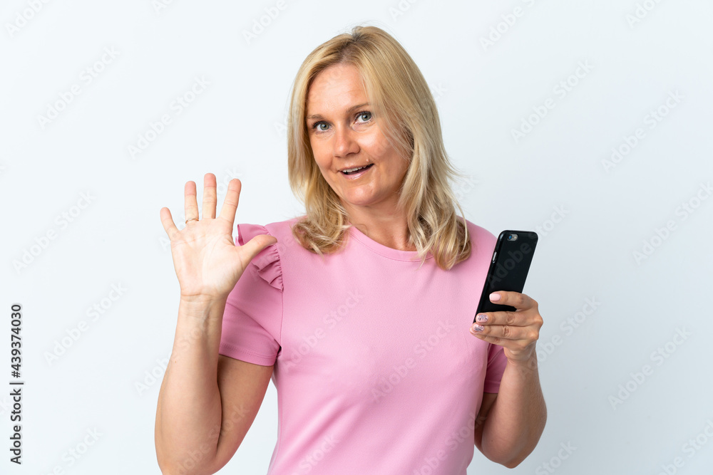 Middle age using mobile phone isolated on white background saluting with hand with happy expression Middle age using mobile phone isolated on white background saluting with hand with happy expression