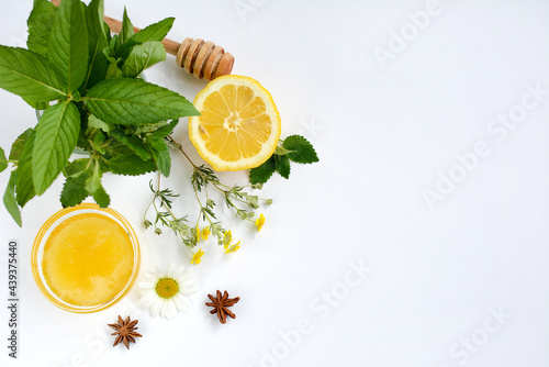 Top view of a cup with honey, lemon, mint, anise and herbs on a white background. Flat lay, copy space