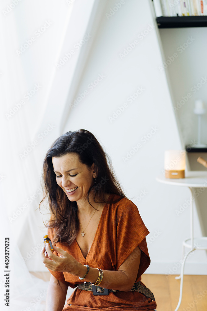 Happy woman with bottle of essential oil Happy woman with bottle of essential oil