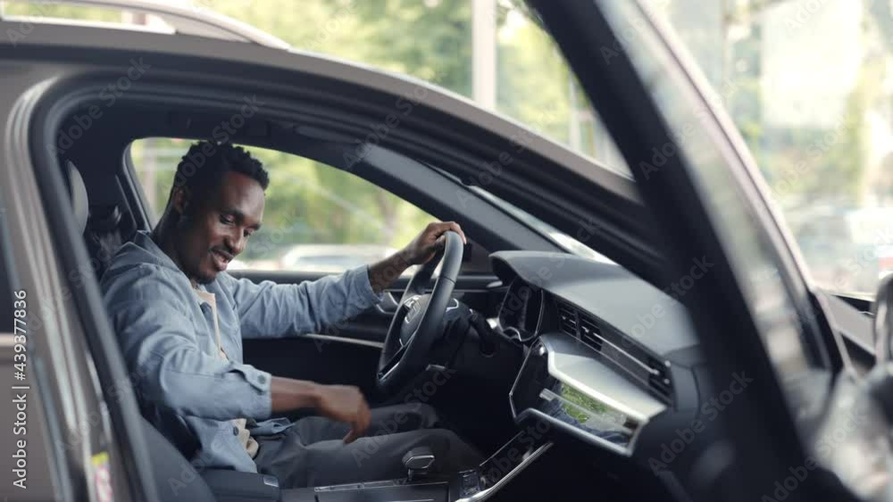 Happy male client examining interior of modern car Happy male client examining interior of modern car