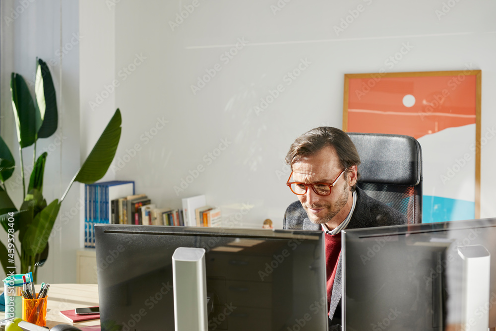 © ALTO IMAGES/Stocksy - Businessman working on computers © ALTO IMAGES/Stocksy - Businessman working on computers