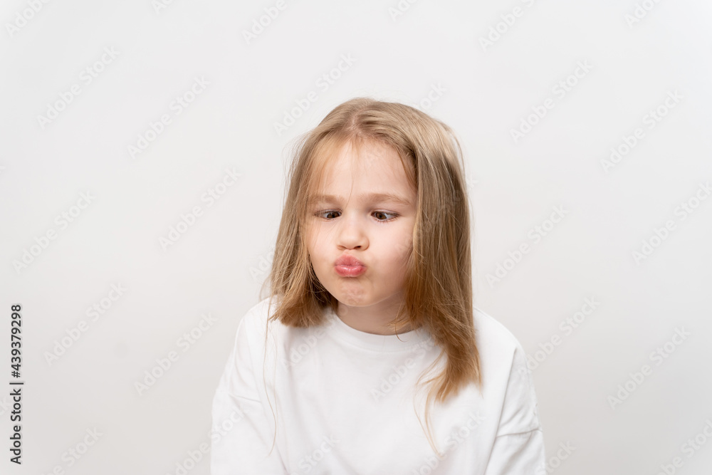 funny little girl grimaces on a white background. happy childhood. vitamins and medicine for the child. funny little girl grimaces on a white background. happy childhood. vitamins and medicine for the child.