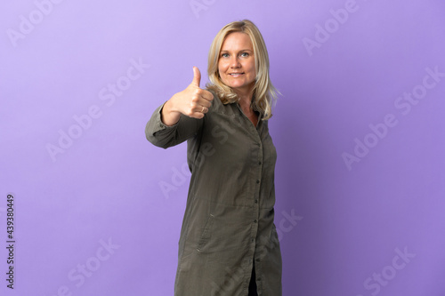 Middle age Lithuanian woman isolated on purple background with thumbs up because something good has happened
