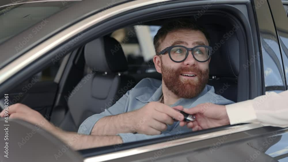 Man sitting in new car and taking keys from female seller Man sitting in new car and taking keys from female seller