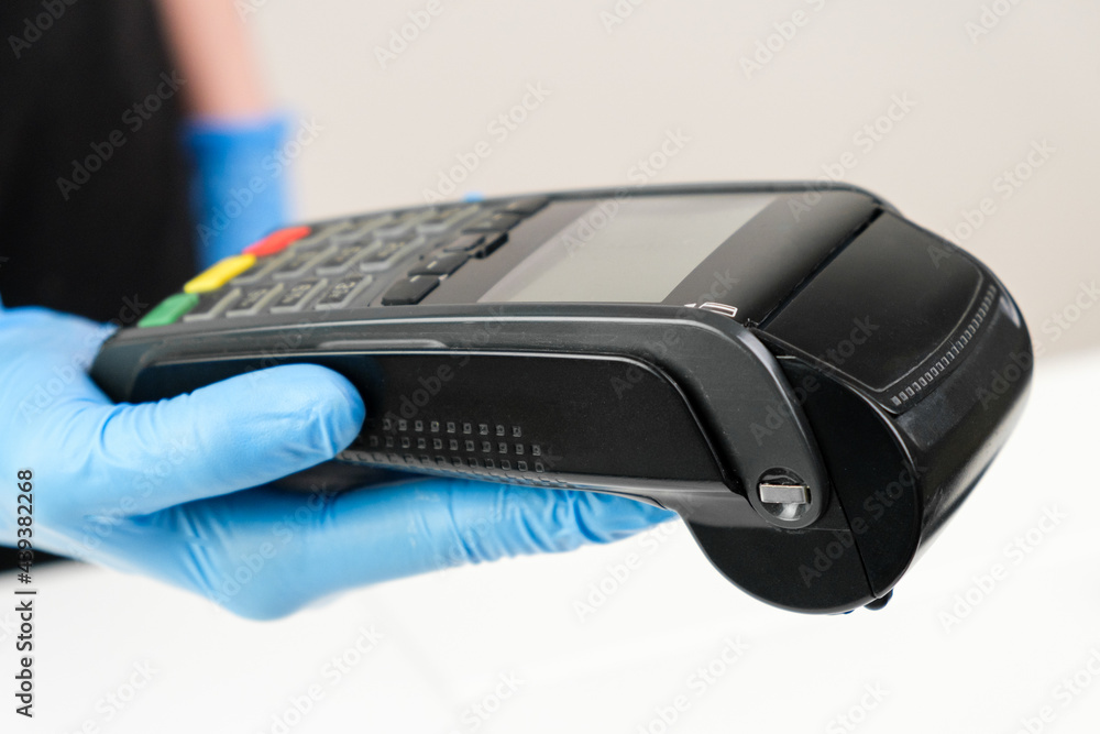 Close up woman in rubber gloves holding a pos terminal. Contactless payment during pandemic using nfc technology Close up woman in rubber gloves holding a pos terminal. Contactless payment during pandemic using nfc technology