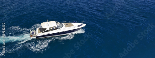 Aerial drone photo of small luxury yacht cruising in deep blue waters of Mykonos island, Cyclades, Greece © aerial-drone