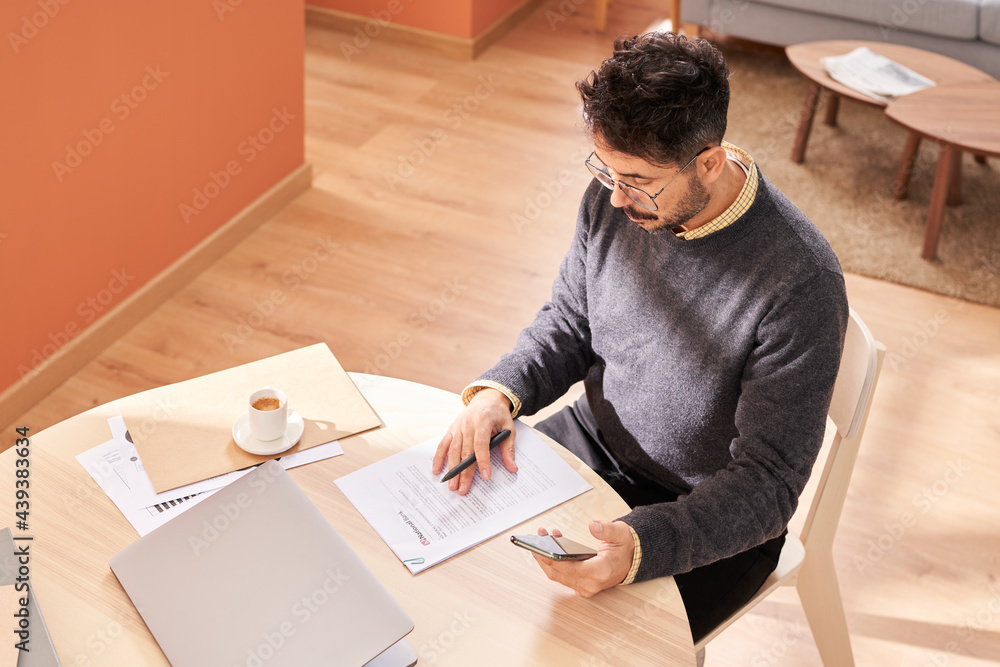 Middle aged freelancer with smartphone doing paperwork Middle aged freelancer with smartphone doing paperwork