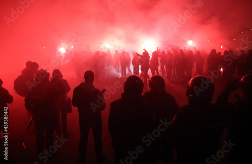 Police looking at football fans with torches © Damir