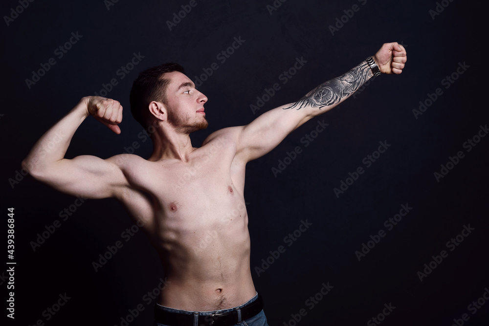 Portrait of a sexy young man with muscular body posing at studio. Dark background. Men's health.