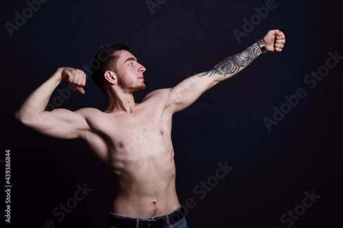 Portrait of a sexy young man with muscular body posing at studio. Dark background. Men's health. © Nastassia