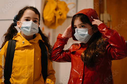 Little kids ready to go to school with mask and raincoat photo