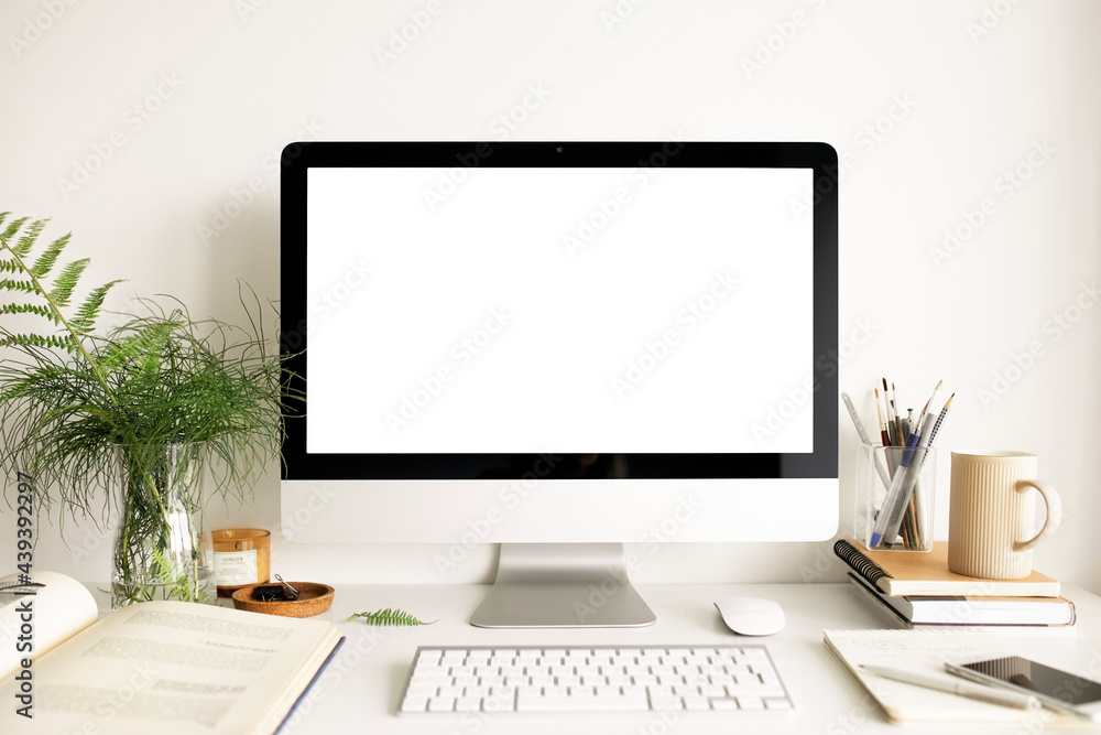 Technology, communication and electronic gadgets concept. Front view of clean stylish home office with desktop computer, open book, mug of tea, fresh fern flowers and statinary items on table Technology, communication and electronic gadgets concept. Front view of clean stylish home office with desktop computer, open book, mug of tea, fresh fern flowers and statinary items on table
