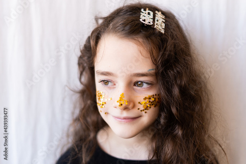 Portrait of little girl with golden glitter of stars on her face photo