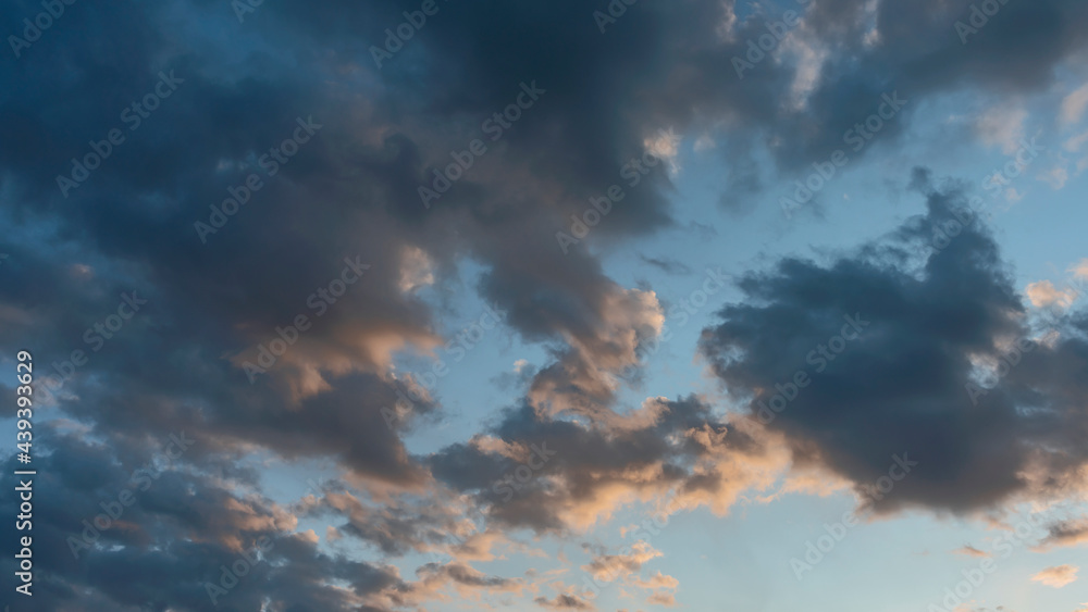 blue sky with dark clouds illuminated by the evening setting sun as a natural background
