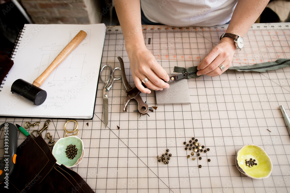 Woman fixes zipper on work bench Woman fixes zipper on work bench