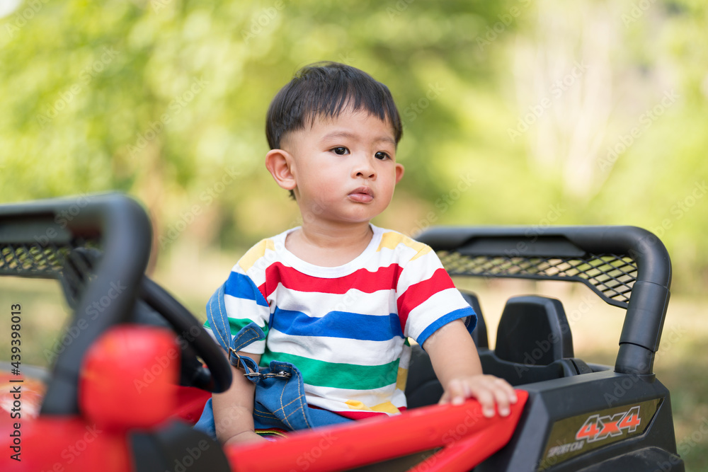 Asian Little boy sitting on a toy car and looking Asian Little boy sitting on a toy car and looking