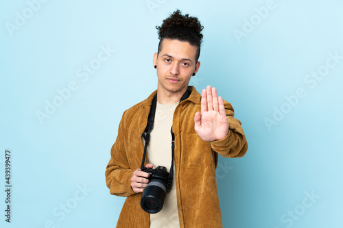 Photographer man over isolated blue background making stop gesture with her hand © luismolinero