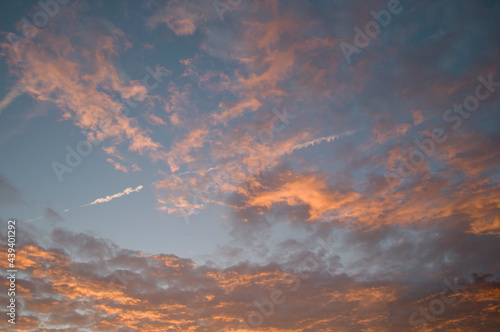 vanilla sunset, gently pink clouds against the background of the sunset sky and the trail of an airplane in the sky, texture,