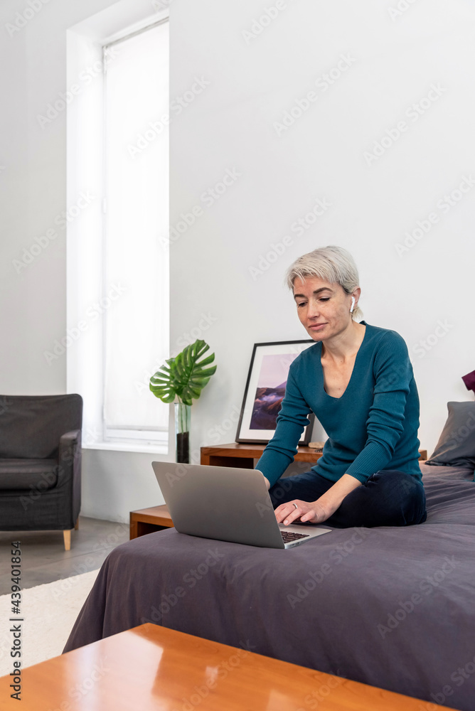 Middle aged woman with a laptop on bed Middle aged woman with a laptop on bed