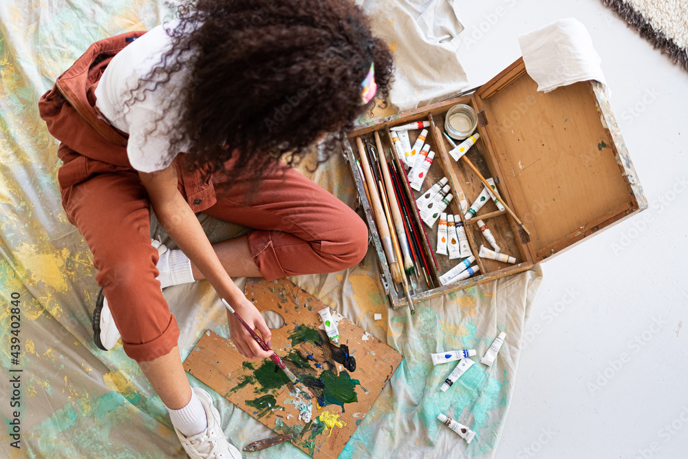 Anonymous mixed race artist woman mixing colors in a painter palette
