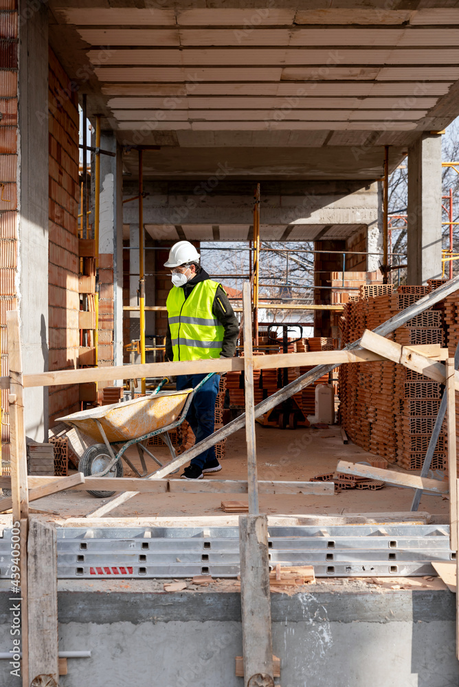 Builder in protective mask working on construction site Builder in protective mask working on construction site