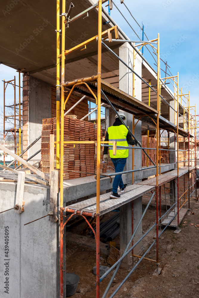 Builder walking on scaffolding on construction site Builder walking on scaffolding on construction site